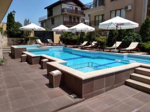 a swimming pool with chairs and umbrellas next to a building at Villa Valeev in Sozopol