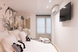 a bedroom with a white bed with a television on a wall at Bilbao Art Lodge Staynnapartments in Bilbao