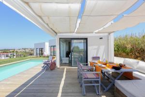a patio with a table and chairs next to a pool at Like-home-T2 house, pool, AC, garden in Ericeira
