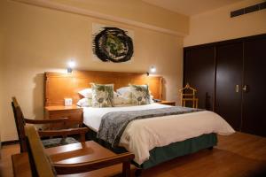 Un dormitorio con una cama grande y una mesa y sillas. en BON Hotel Bloemfontein Central, en Bloemfontein