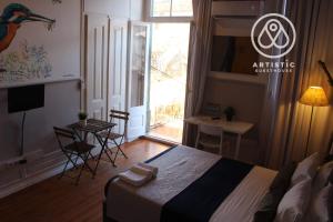 a bedroom with a bed and a table and a window at ArtisticGuesthouse in Tomar