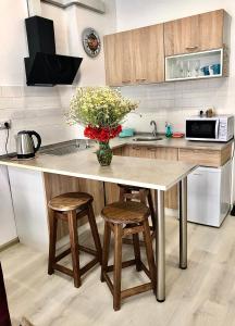 uma cozinha com uma mesa com bancos e um vaso de flores em Sмарт студія з терасою !! em Yuzhne