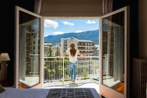 una donna in piedi su un balcone che guarda fuori da una finestra di Gran Hotel de Jaca a Jaca