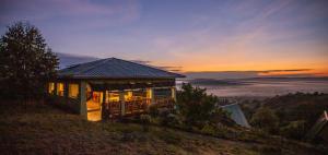 a house on a hill with the sunset in the background at Hyena Hill Lodge in Sanga