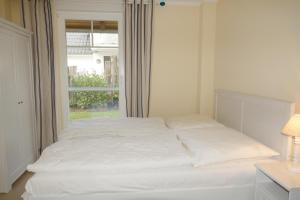 uma cama branca num quarto com uma janela em Ibykus em Prerow