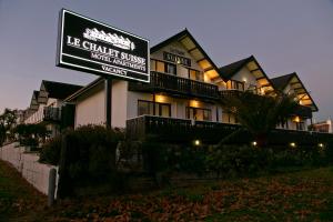 a large building with a sign in front of it at Le Chalet Suisse Motel Taupo in Taupo