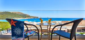 a table with chairs and a glass of wine at Hotel & Spa S'Entrador Playa in Cala Ratjada