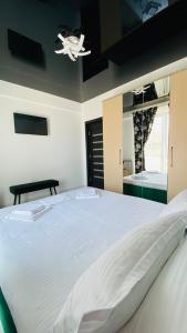 um quarto com uma grande cama branca e uma ventoinha de tecto em Maze Apartment em Mamaia Nord – Năvodari