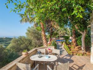 a table and chairs on a patio with trees at Villa Clio with Pool Stalos Crete in Stalos