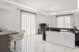 a kitchen with white cabinets and a table and chairs at BillyMare central Glyfada apartment in Athens