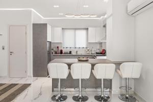 a white kitchen with white chairs and a counter at BillyMare central Glyfada apartment in Athens