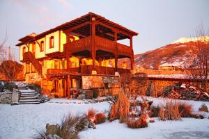 una grande casa in legno con neve per terra di Старата къща / село Тъжа a Tŭzha