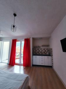 a room with a bed and a kitchen with red curtains at Kale Apartments Trpejca SUP and bikes included in Ohrid