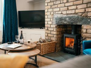 a living room with a brick fireplace with a table and a fire place at The Deekabout in Keswick