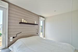 a bedroom with a white bed and a window at Chalet pour 8 dans résidence avec piscine chauffée in Brétignolles-sur-Mer +26 photos