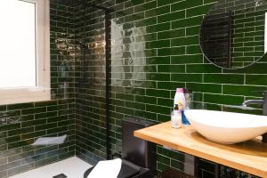 een groene betegelde badkamer met een wastafel en een spiegel bij Zabalburu in Bilbao