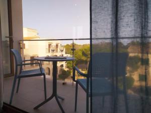 stół i 2 krzesła na balkonie z oknem w obiekcie Apartamentos Villa Primera w mieście Cala Figuera