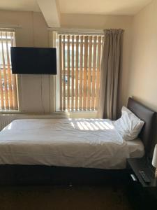 a bedroom with a bed with a television and a window at Ivy Green B&B in Huddersfield
