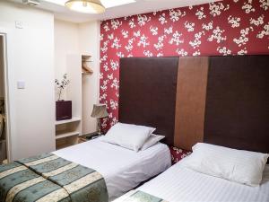 1 dormitorio con 2 camas y pared roja en The Golf Tavern, en Haddington
