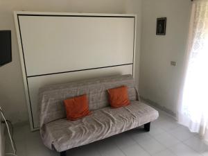 two orange pillows sitting on a couch in a room at Appartamento in villaggio, a 150mt dal mare in San Teodoro