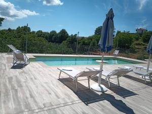 a patio with two chairs and an umbrella and a pool at Da Fabiana, Ristorante e Camere in Alta Langa - adults only in Bossolasco