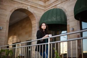 a woman standing on a railing holding a coffee cup at Holiday Inn Aktau, an IHG Hotel in Aktau