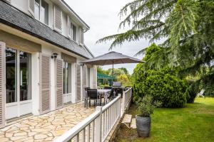 a porch with an umbrella and a table and chairs at La Déferlante - Maison familiale à Cancale in Cancale
