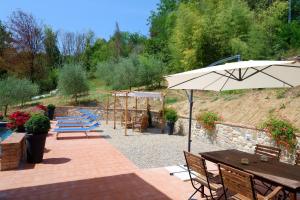 un patio con mesas, sillas y una sombrilla en Il Nido di Margherita, en San Giovanni Valdarno