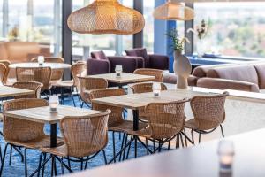a row of tables and chairs in a restaurant with windows at Scandic CPH Strandpark in Copenhagen