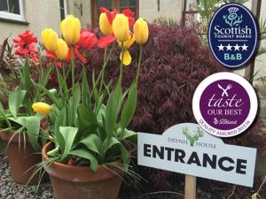 a bunch of flowers in pots next to a sign at Old Drynie House, in Inverness +11 photos