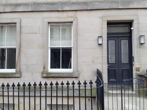 um edifício com uma porta preta e duas janelas em Edinburgh Nine em Edinburgo