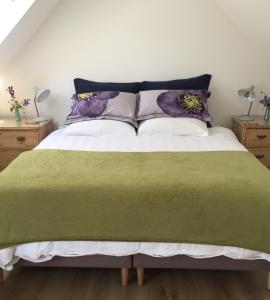 una camera da letto con un letto con una coperta e cuscini verdi di The Loft at Craiglea a Pitlochry