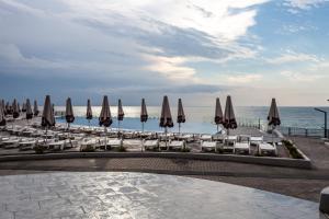 a row of umbrellas and chairs and the ocean at Optima Collection Miramar Chornomorsk in Chornomorsk