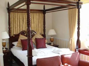 Schlafzimmer mit einem großen Himmelbett und roten Kissen in der Unterkunft Downe Arms Country Inn in Wykeham