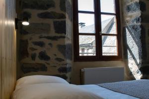 a bedroom with a stone wall and a window at Hôtel Restaurant Le Bardière in Laguiole