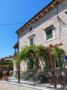 un edificio de piedra con persianas verdes y una valla en Casa Nonna Tereza en Premantura