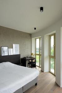 een slaapkamer met een bed, een bureau en ramen bij Parkhotel Waregem in Waregem