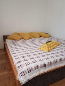 ein Bett mit gelben Kissen und einer karierten Decke in der Unterkunft Apartments Petar btw. Split and Omiš in Jesenice