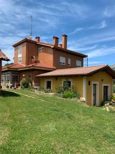 a large house with a grass yard in front of it at Hostel Arenos in Velilla del Río Carrión