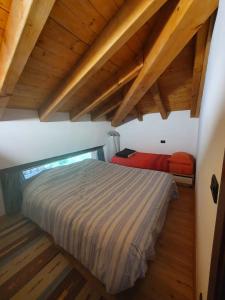 a bedroom with a bed in a room with wooden ceilings at Mansarda bilocale centro Brusson in Brusson