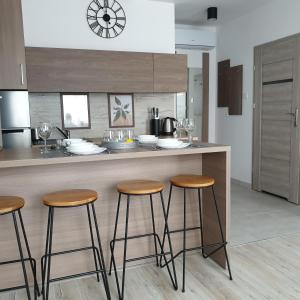 una cocina con taburetes de madera en una barra de cocina en Q Apart SILVER - garaż, klimatyzacja, Netflix, FV, STUDIO, en Łódź