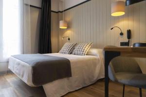een slaapkamer met een bed, een bureau en een stoel bij Hotel SUB in Asnières-sur-Seine