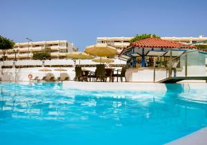 een zwembad met een tafel en parasols bij Rey Carlos in Playa del Inglés