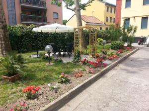 een tuin met een tafel, een parasol en bloemen bij Hotel Garden in Milaan