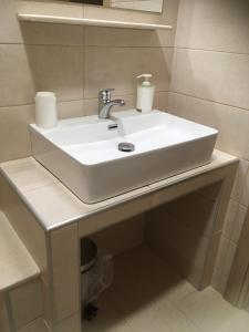 La salle de bains est pourvue d'un lavabo blanc sur un comptoir. dans l'établissement Marco's Appartments, à Potidée