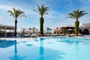 une grande piscine bordée de palmiers et de chaises dans l'établissement MarBella, Mar-Bella Collection, à Agios Ioannis Peristerion