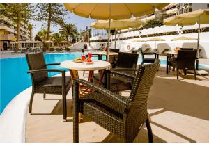 een tafel met stoelen en een parasol naast een zwembad bij Rey Carlos in Playa del Inglés