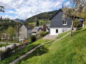 a house on a grassy hill with a church at Ferienwohnung sauerland-ruhe in Schmallenberg