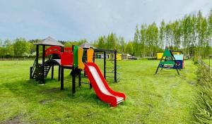 un parque infantil con un tobogán en un campo en Piejūras Nams en Ķesterciems