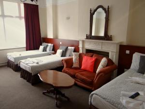 a hotel room with two beds and a couch and a mirror at Charlotte Guest House in London